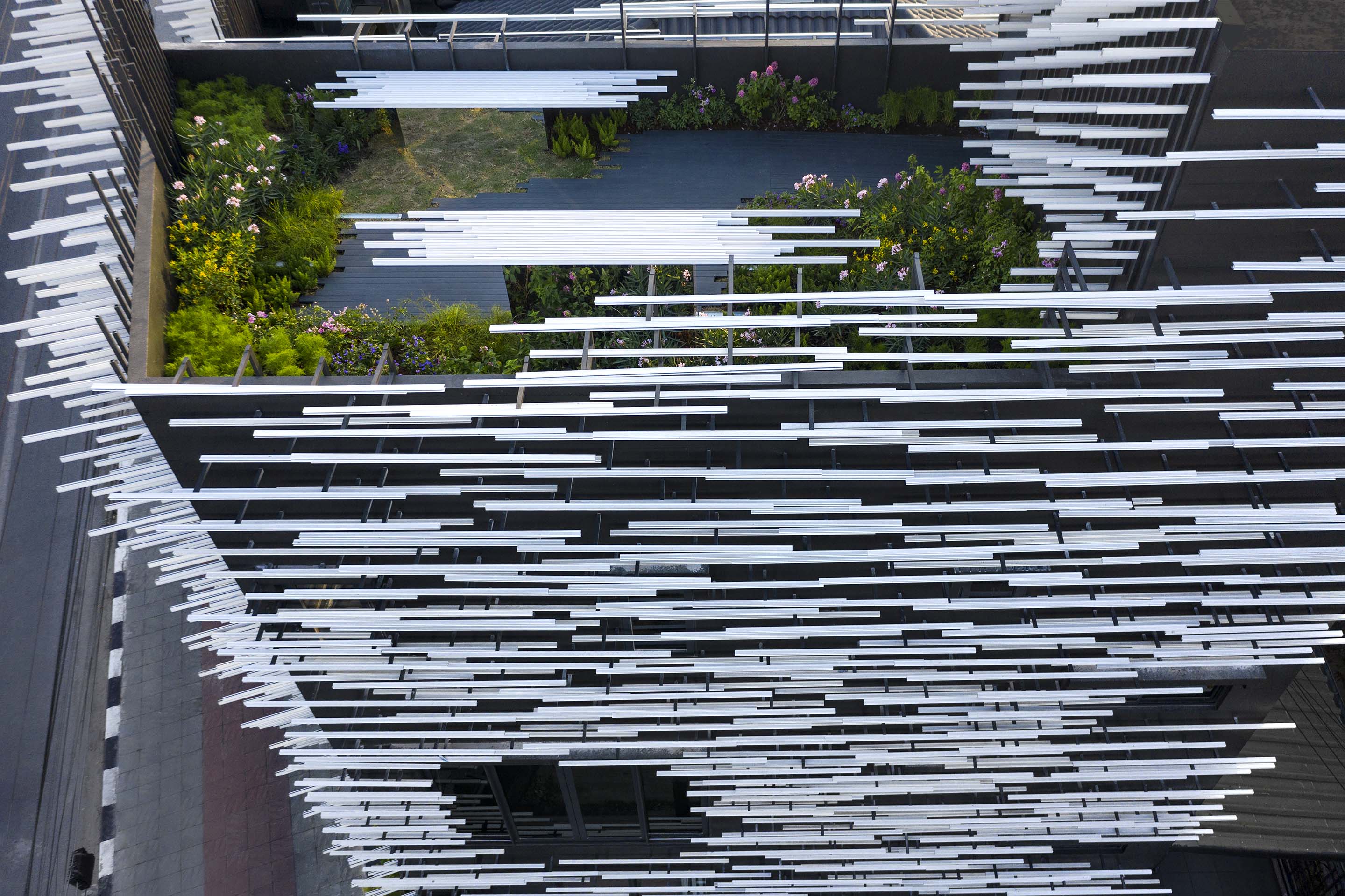 Museum of Modern Aluminum Thailand: an aerial view of a planted courtyard framed by rows of slender white metal rods.