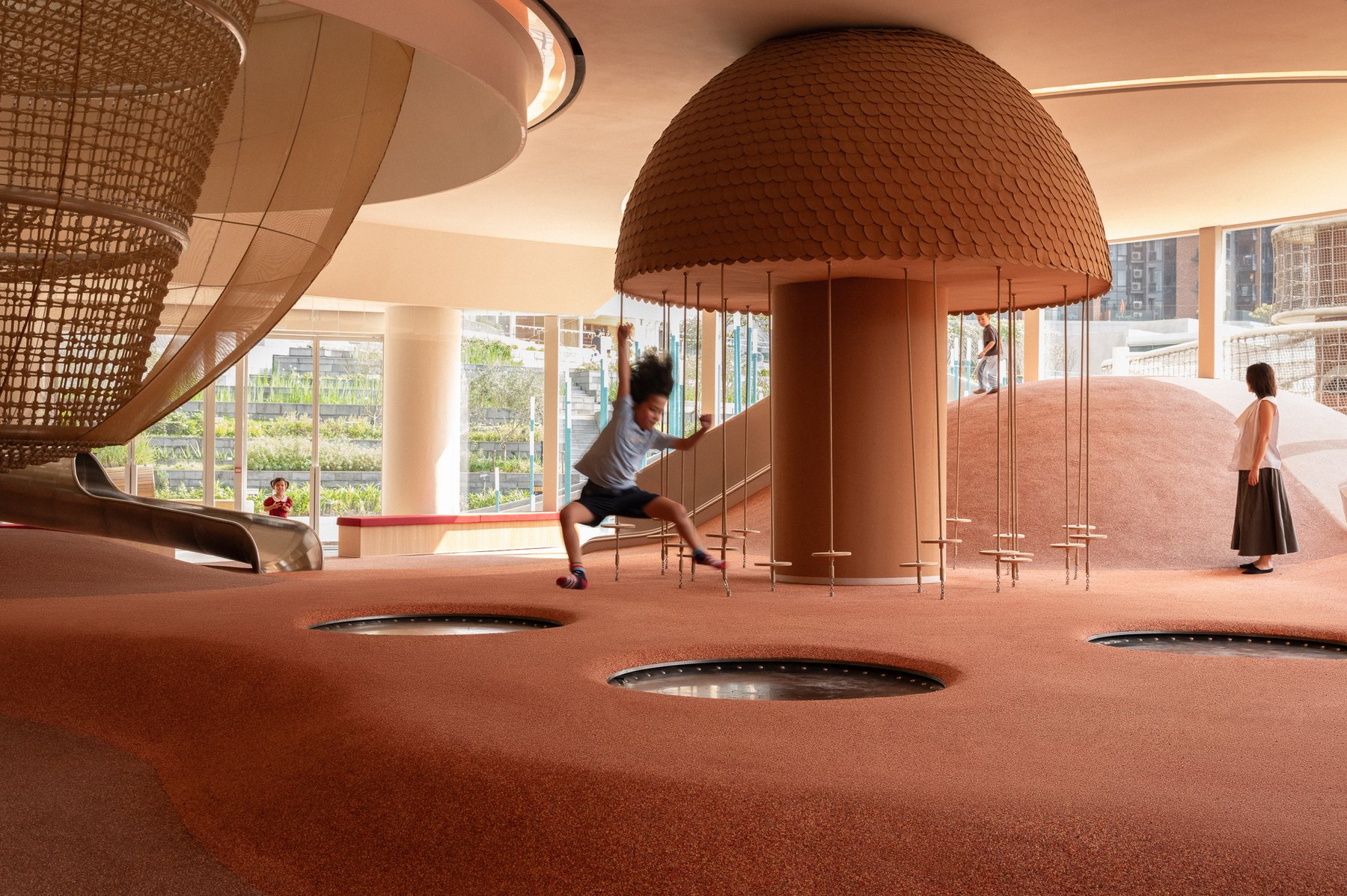 The indoor play area at Sky House, with a rope climbing tower rising into a woven dome over a terracotta floor.